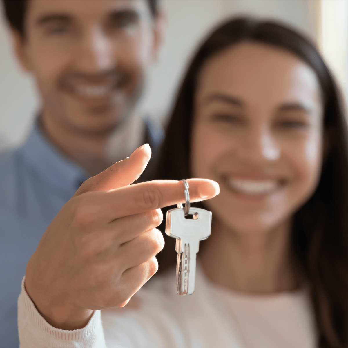 A couple proudly holds a key to their new home, symbolizing their achievement as first time buyers.