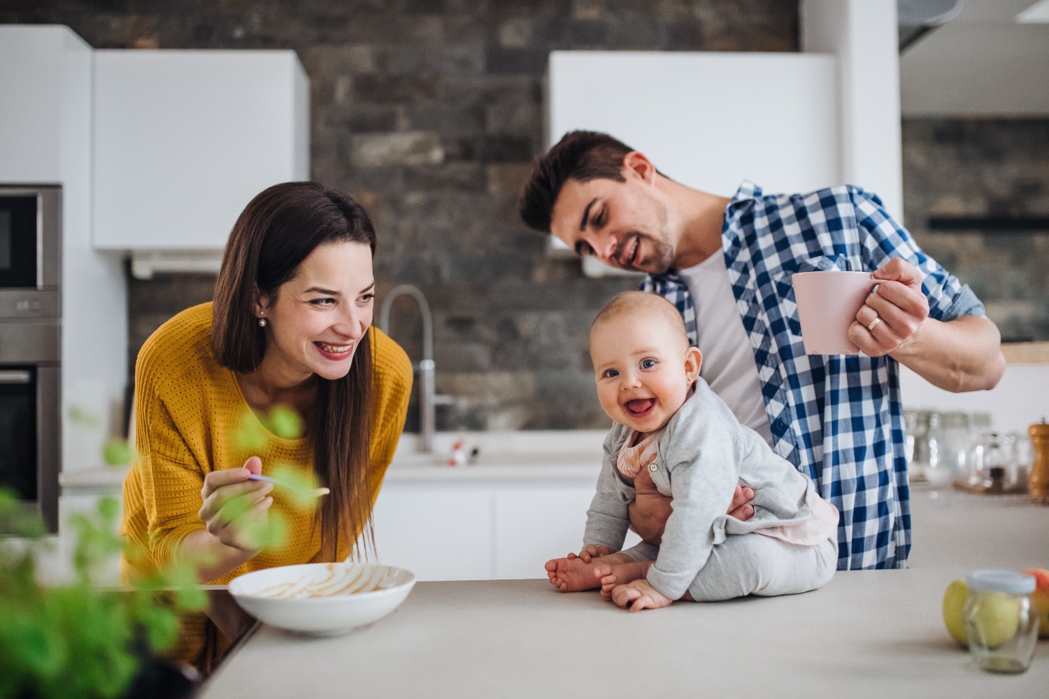 A family of three gathered in a modern kitchen.