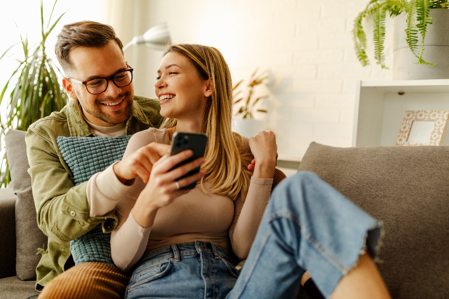 Overjoyed young couple celebrating on sofa with a successful mortgage application.